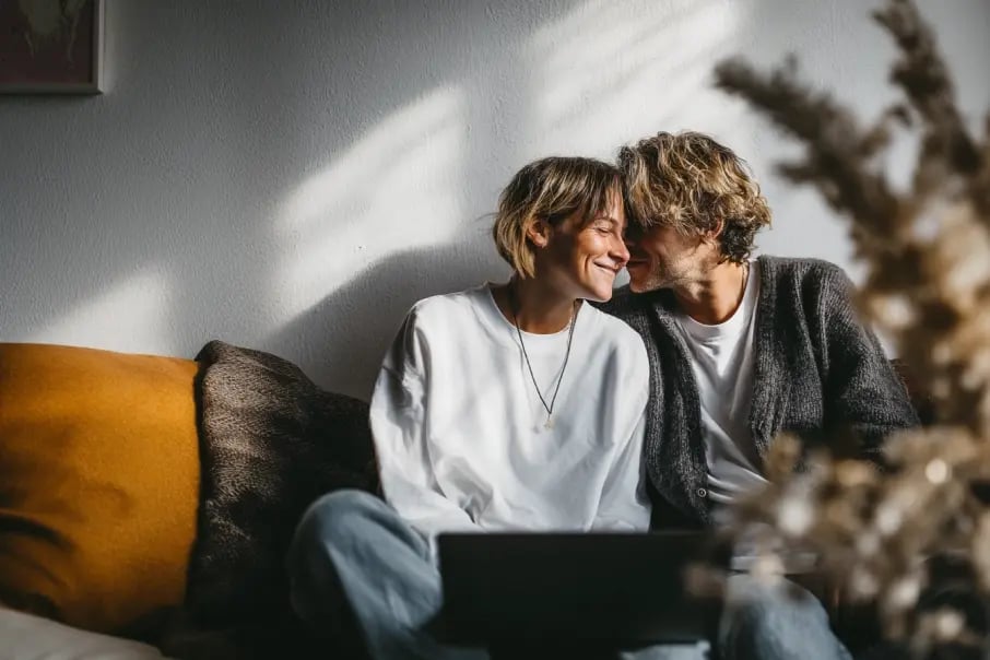 A couple sitting on a couch looking at each other, symbolizing trust and privacy while storing personal files securely with Tresorit Basic.