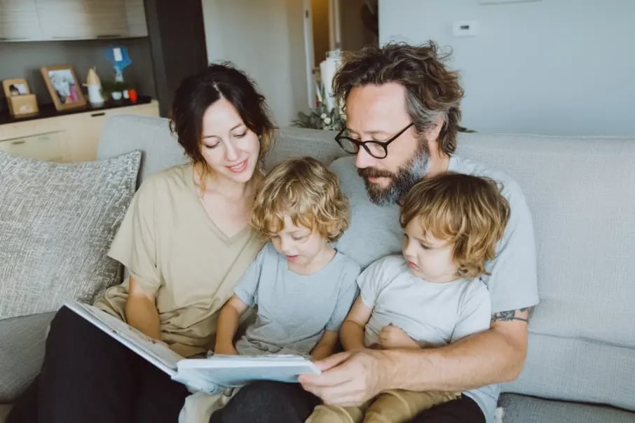 Family of four on a couch looking at a photo album, representing private and secure photo storage and sharing with Tresorit Family.