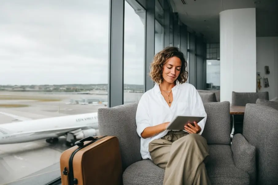 Professional woman in an airport lounge using a tablet, highlighting secure access to business files with Tresorit Professional encrypted cloud.